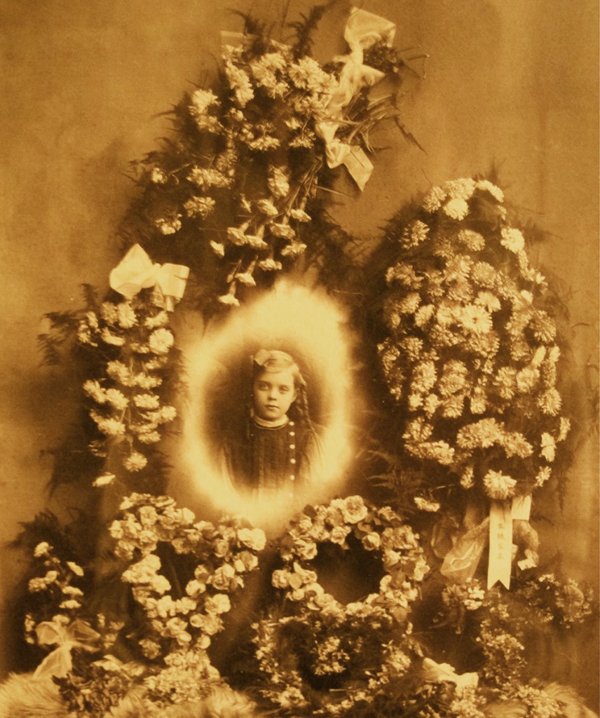 Early examples of trick photography were used to create funeral tableaus, like image of a young girl collaged onto floral arrangements, circa early 1900s.